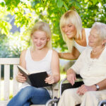 Daughter is reading to elder guardian and elder outside