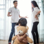 parents arguing in front of daughter who buries herself in stuffed bear