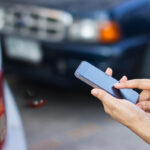 woman using smartphone to call roadside after car accident