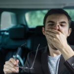 drowsy driver yawning with hand to mouth